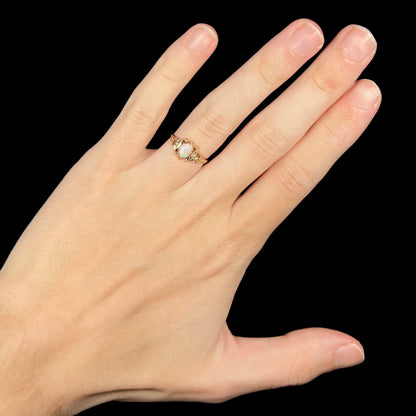 Hand wearing women's antique Victorian era 9k gold opal ring under LED studio light