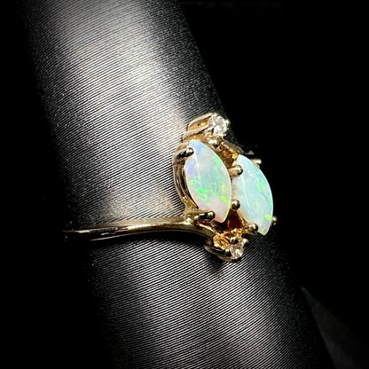 A ladies' gold ring mounted with two marquise cut opals and two diamond accents.