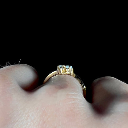 A ladies' gold ring mounted with two marquise cut opals and two diamond accents.
