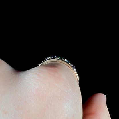 A ladies' yellow gold band set with green, dark blue, light blue, and light purple stones.