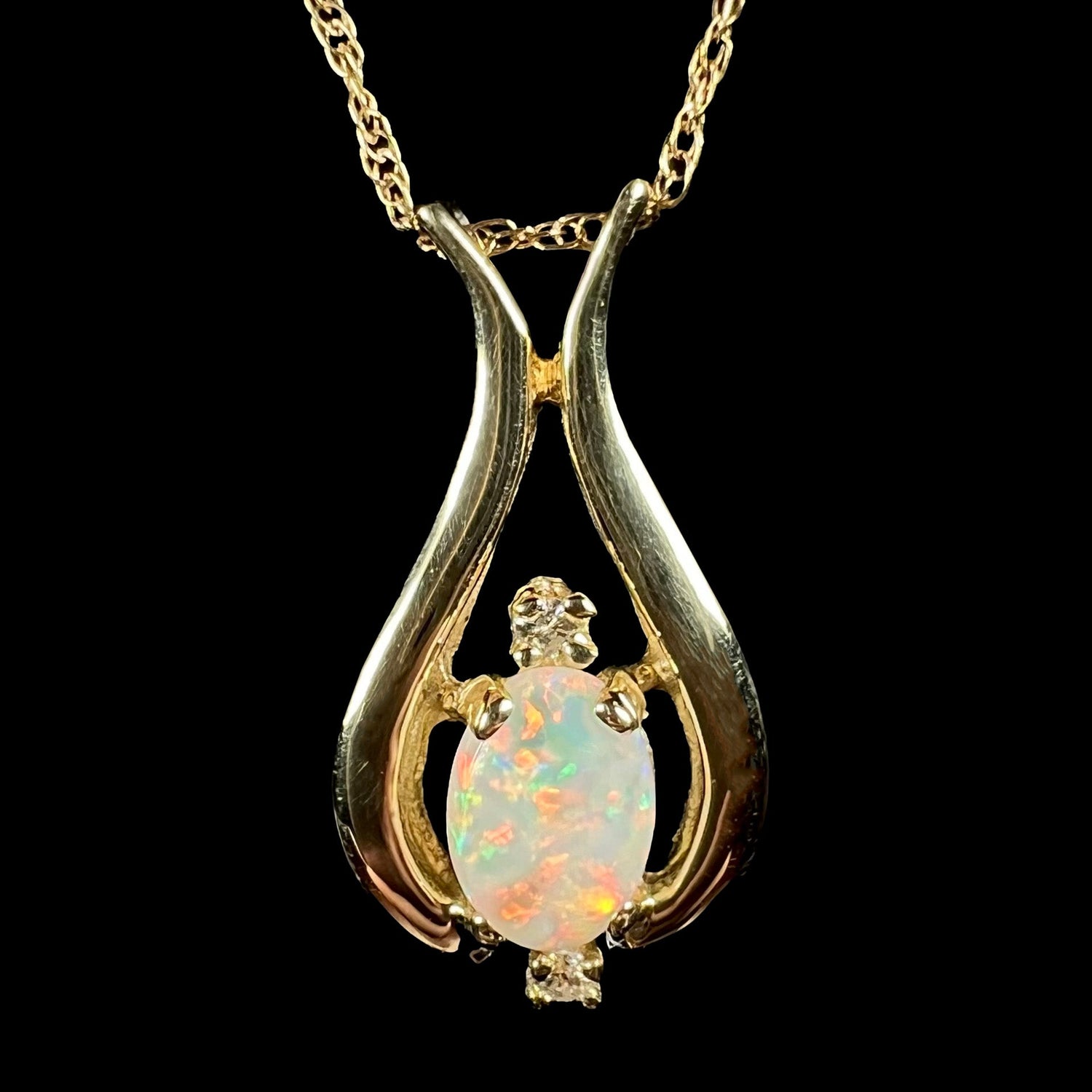 A yellow gold necklace on a chain set with a natural white opal and two diamonds.