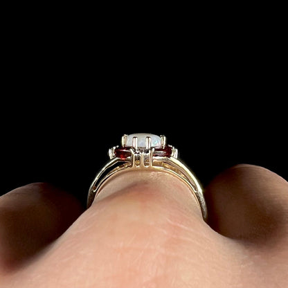A ladies natural opal ring in yellow gold.  The opal is surrounded by red marquise cut garnets and diamonds.