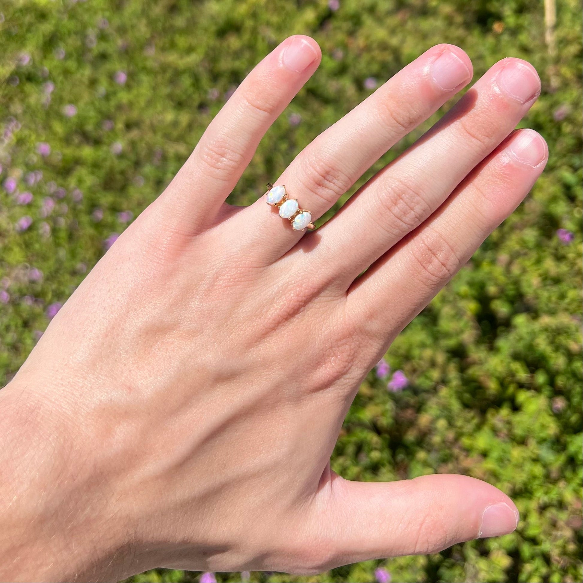 A vintage yellow gold ring mounted with three oval cut white Australian opals.