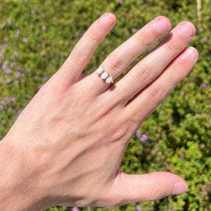A vintage yellow gold ring mounted with three oval cut white Australian opals.