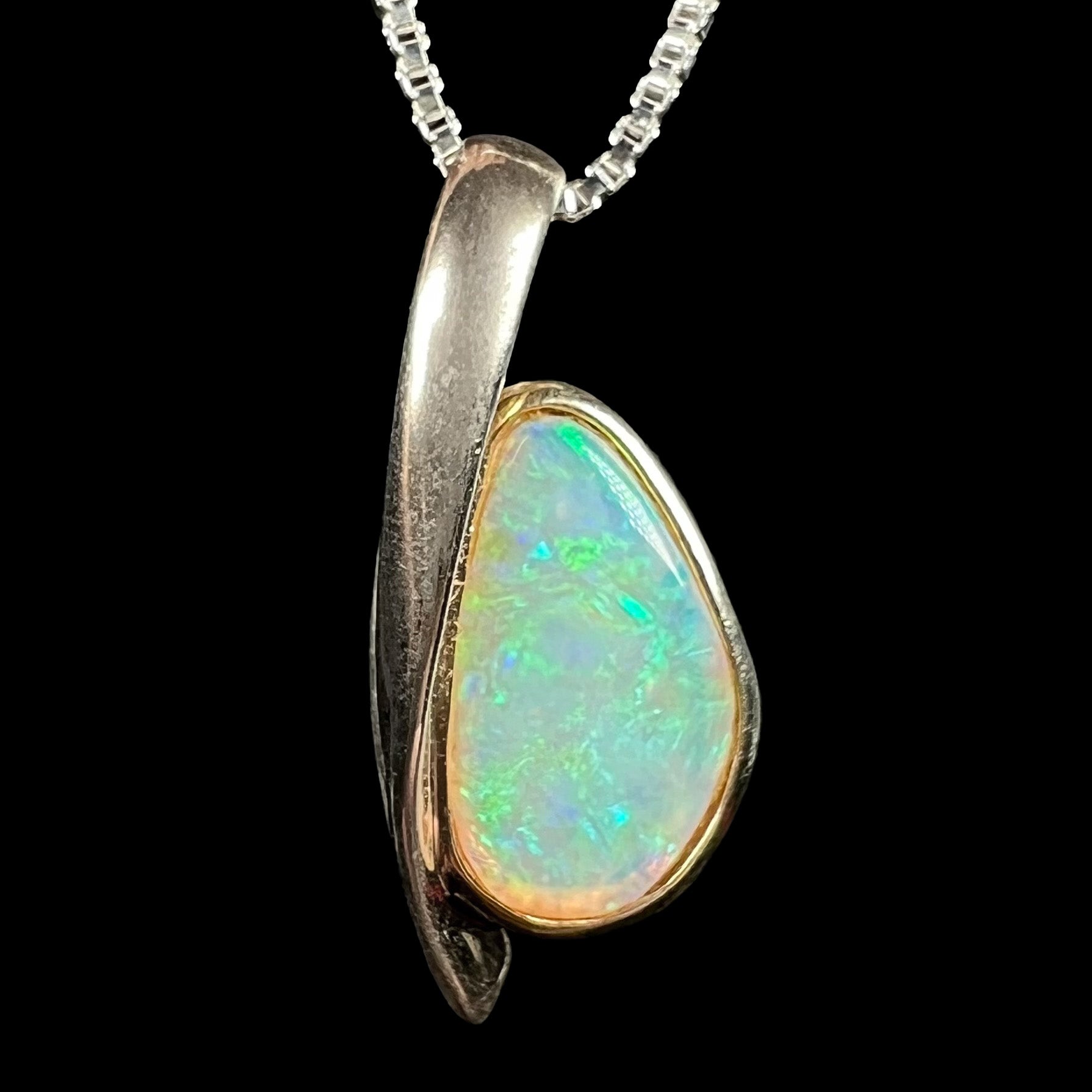 A green Australian crystal opal necklace in sterling silver shown close-up against a black background.