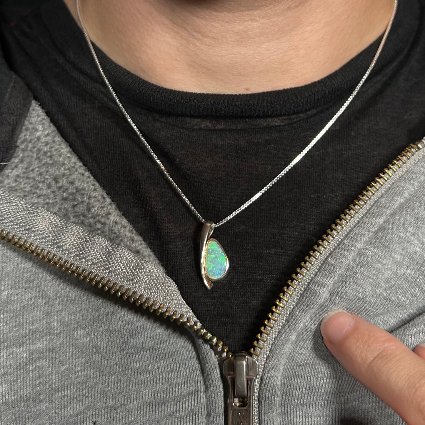 A green Australian crystal opal necklace in sterling silver shown worn around a neck against a dark shirt.