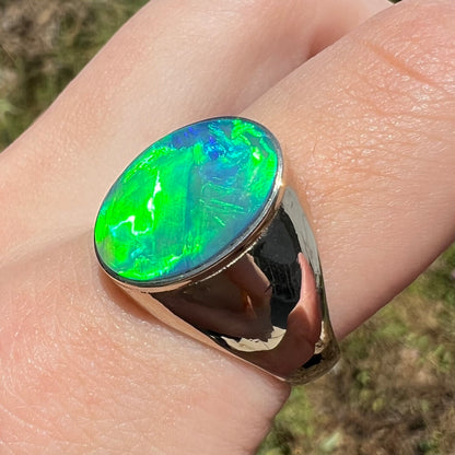 Green Australian crystal opal men's ring in 14k white gold, shown on finger from angle in natural light