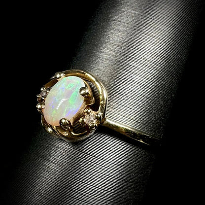 Green flashes are seen in a Coober pedy opal and diamond ring.  Mounted in yellow gold, the ring is seen from an angled view.