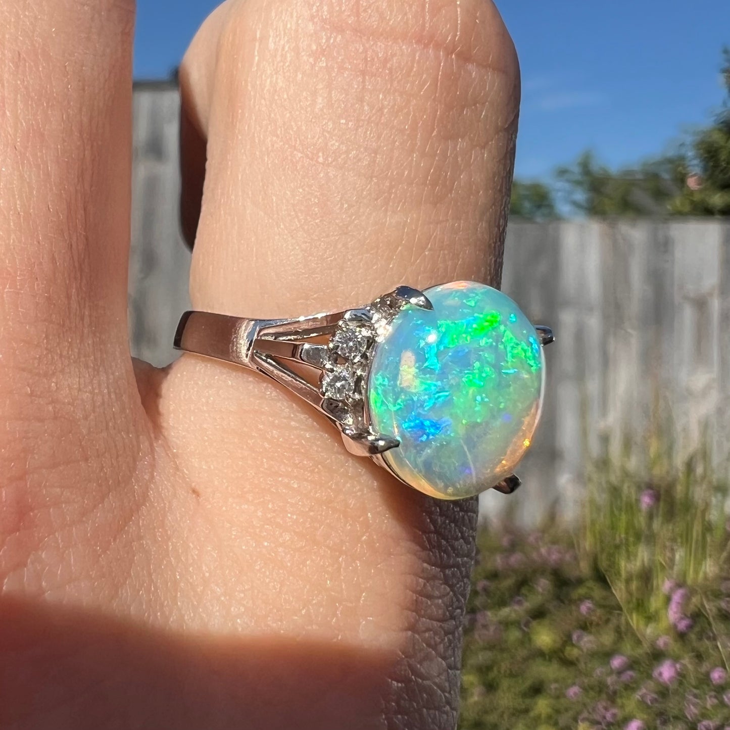 A platinum filigree ring set with a Lightning Ridge crystal opal and diamond accents.