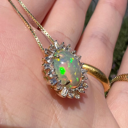 Angled close-up of yellow gold Ethiopian opal slide pendant in hand.  The opal has brilliant green flashes in sunlight.