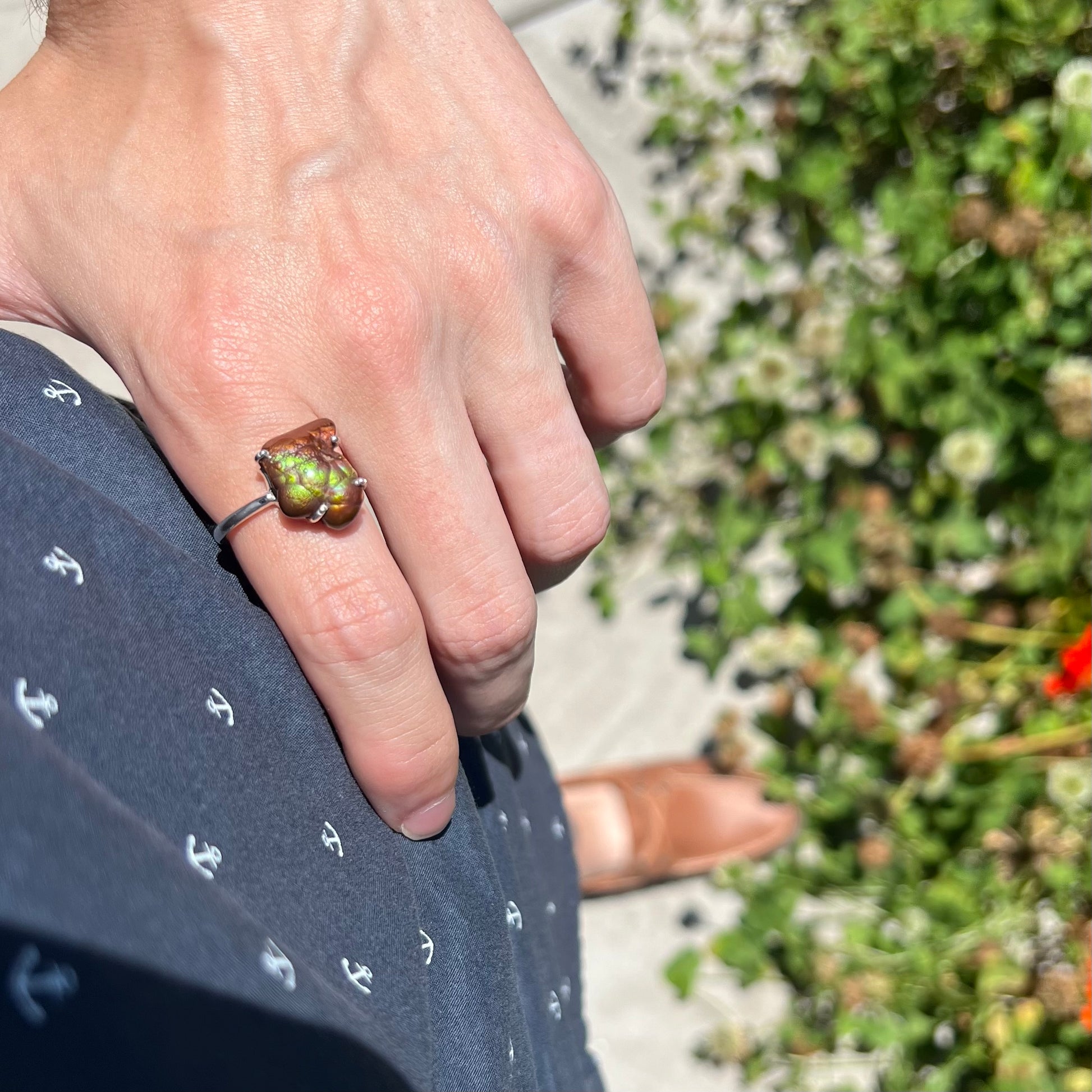 Fire agate ring worn on hand resting on hip in natural sunlight showing bright green fire.
