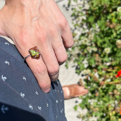 Fire agate ring worn on hand resting on hip in natural sunlight showing bright green fire.