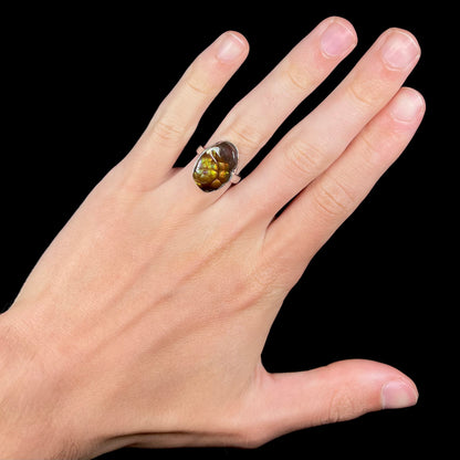 A sterling silver Mexican fire agate ring with green iridescence, worn on a hand.