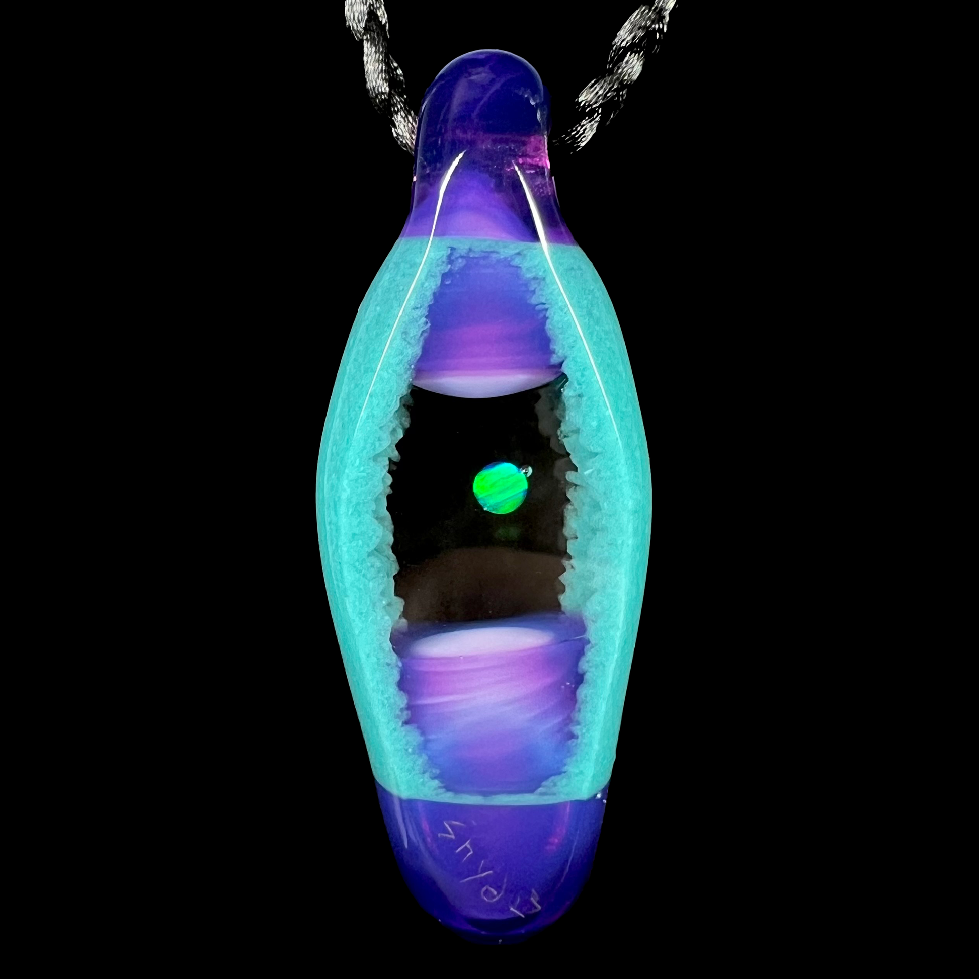 Back side of a green lab-created opal and glass pendant, shown on a black cord against a black backdrop.