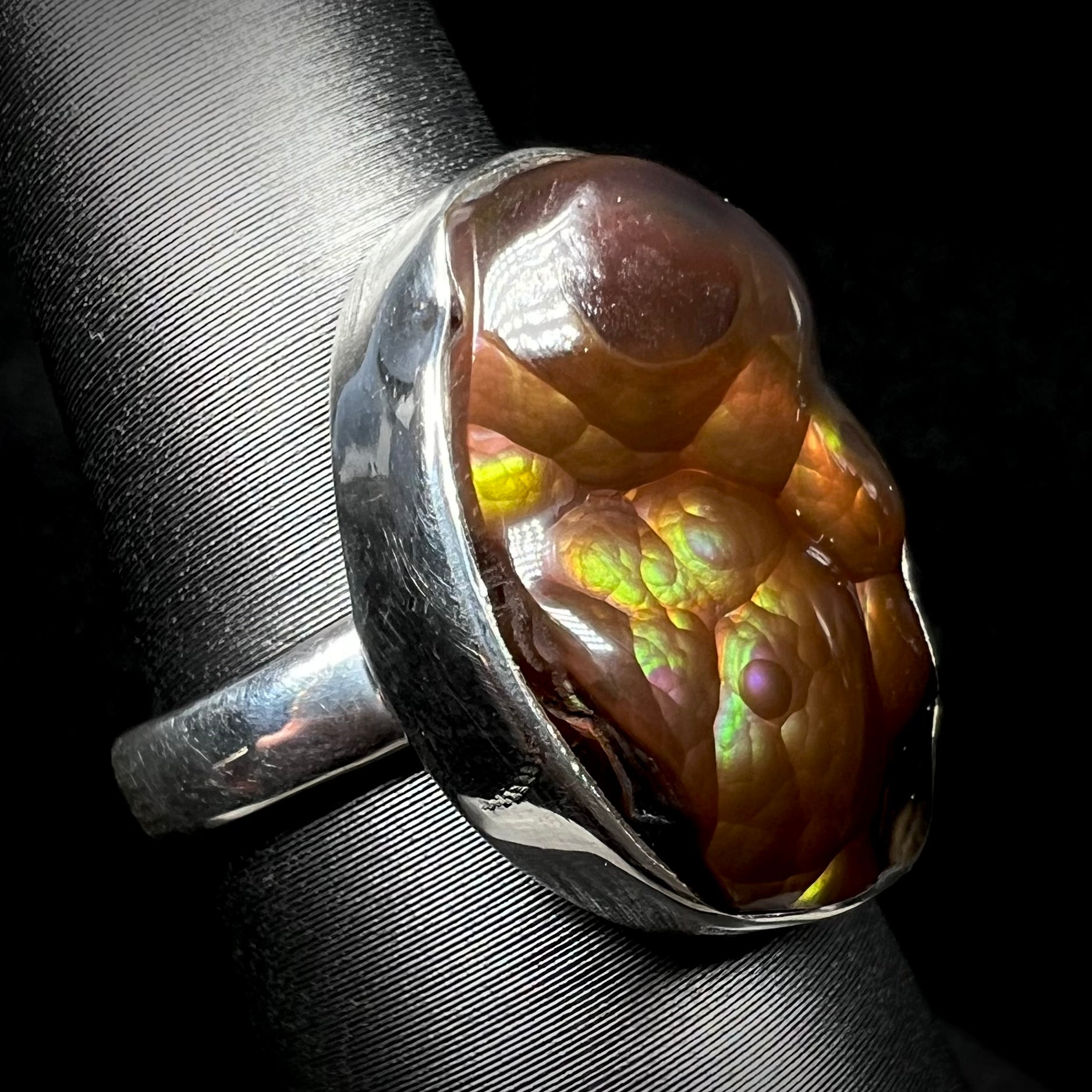 A sterling silver Mexican fire agate ring with green and purple iridescence shown at an angle.