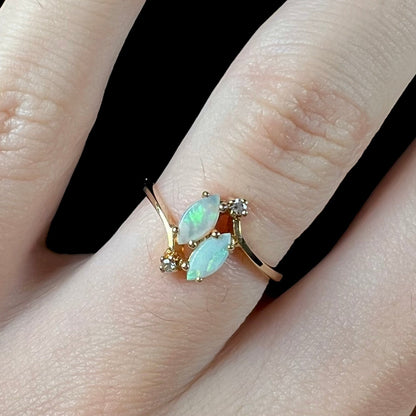 A ladies' gold ring mounted with two marquise cut opals and two diamond accents.