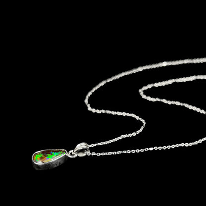 A natural, pear shaped Australian boulder opal with blue, purple, and green colors bezel set into a sterling silver necklace.