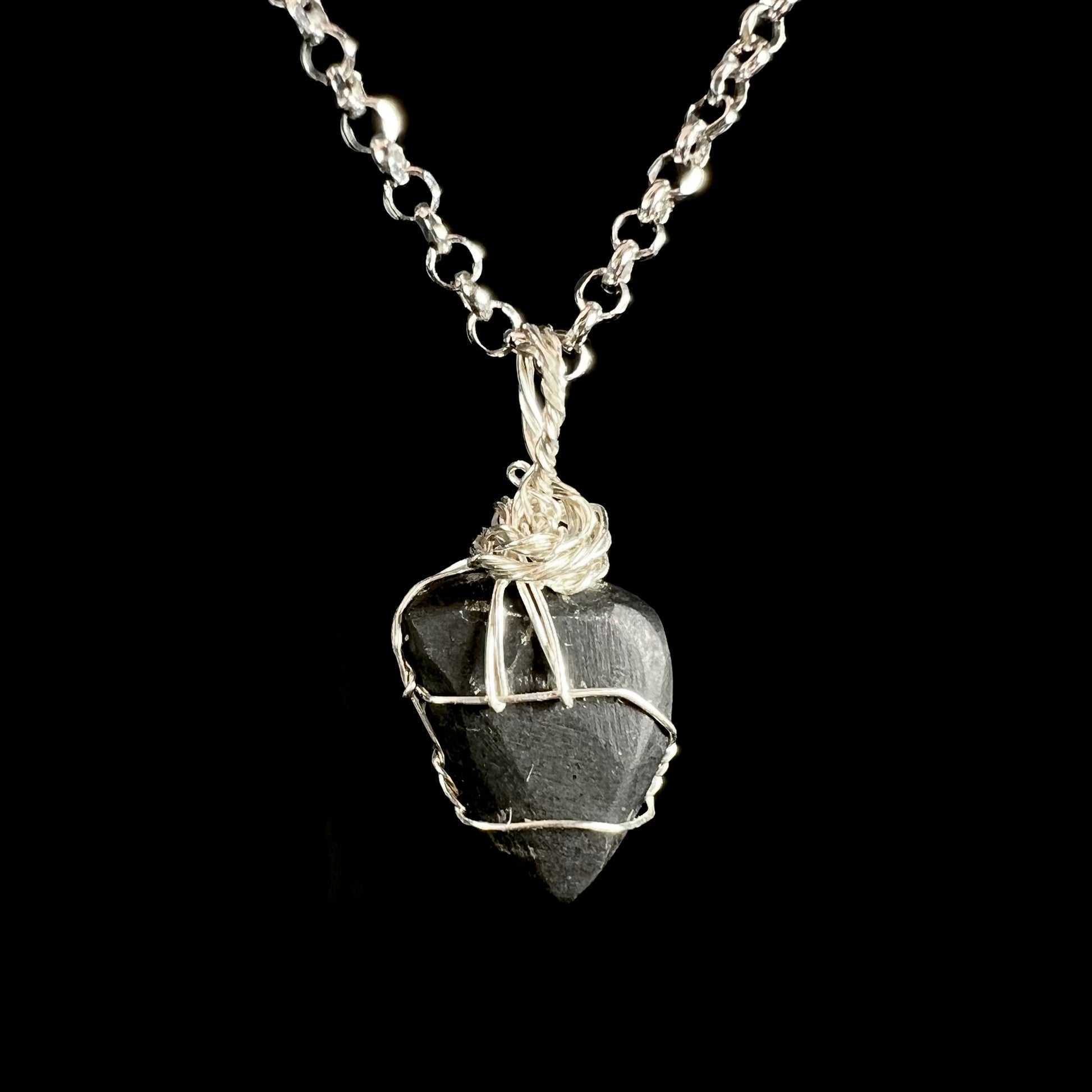 Back side of hand-wrapped sterling silver opal doublet pendant shown on a chain against a black background.