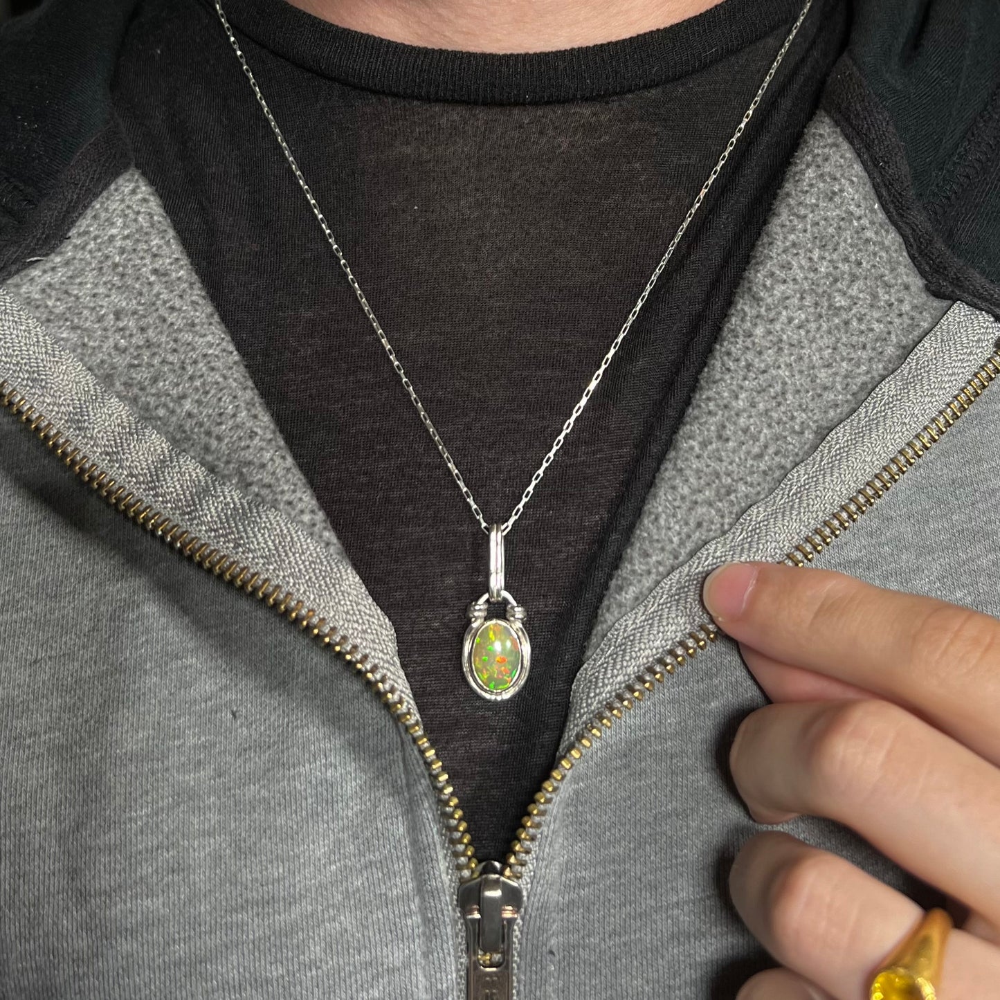 A colorful sterling silver Ethiopian opal necklace worn around a neck against a dark shirt.