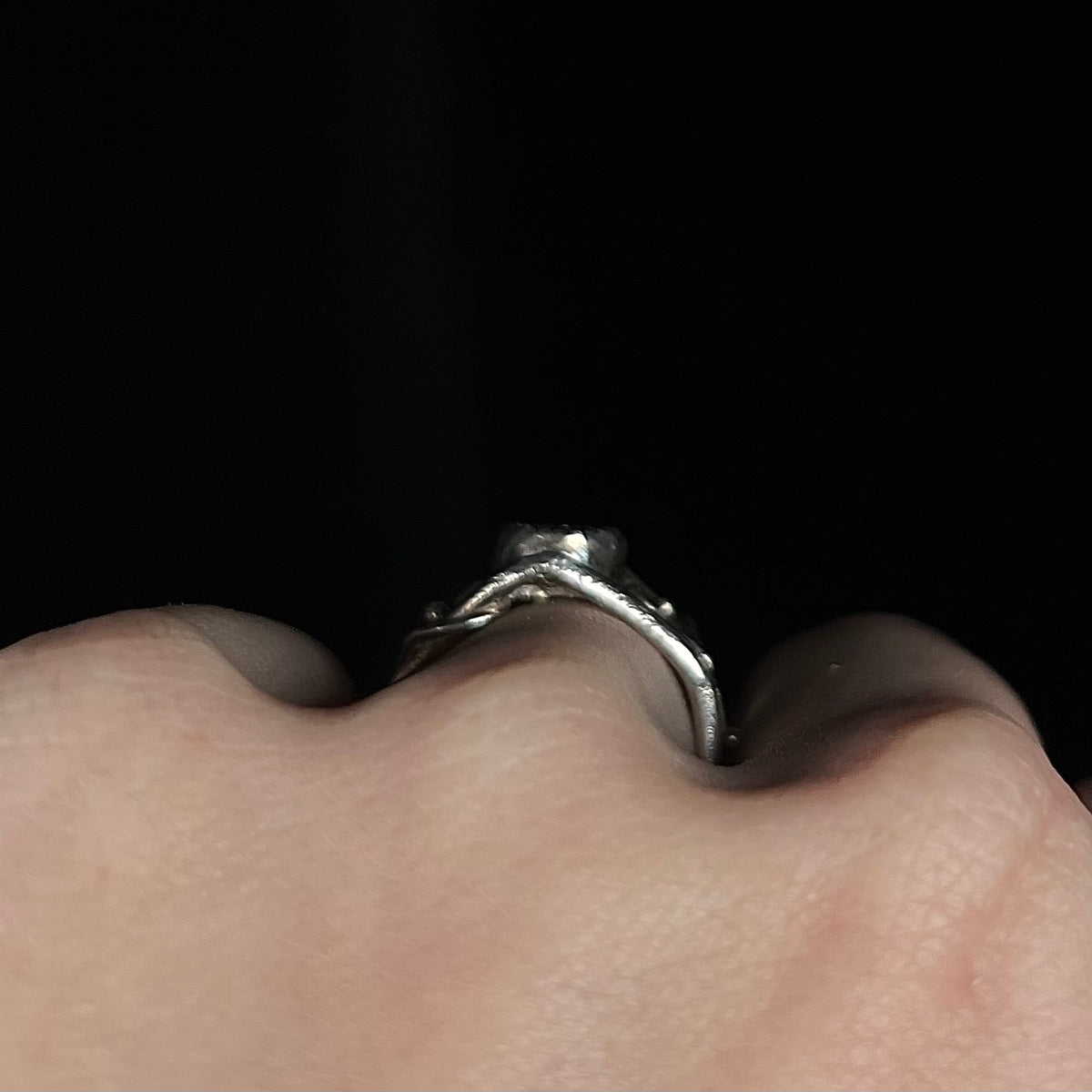 Side profile gallery view of sterling silver bezel set ring with handmade bridge design, worn on finger