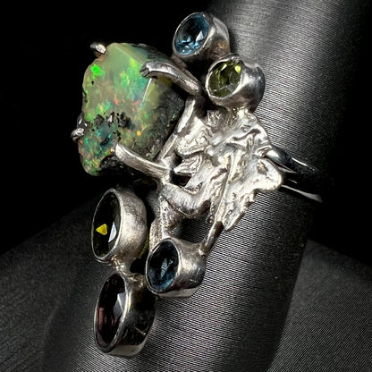 Angled view of a silver men's ring set with rough Virgin Valley opal and gems with a female figure design.