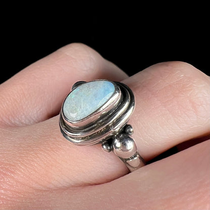 Angled close-up of A handmade Boho-style sterling silver opal ring set with an Australian opal, worn on a finger.