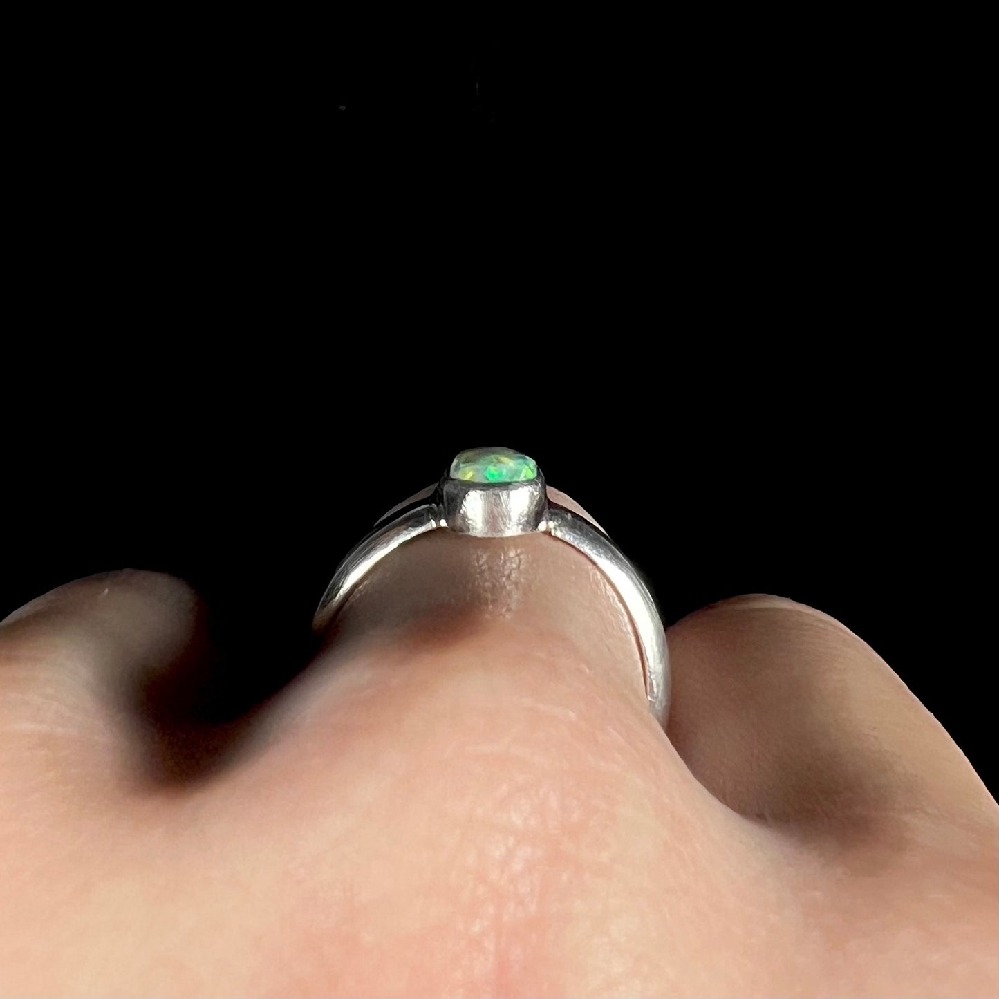 Side profile gallery view of handmade silver opal ring, worn on hand