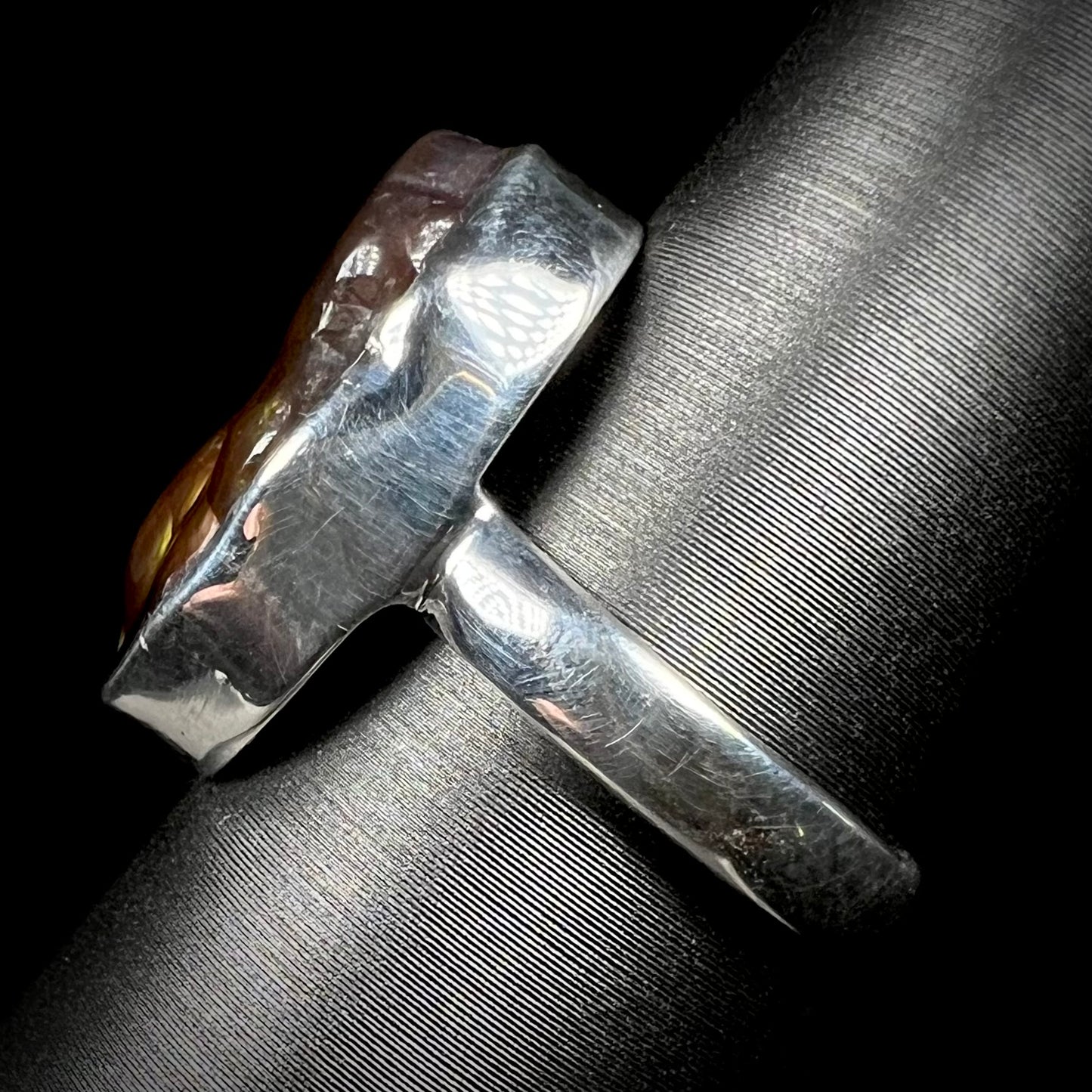 Side view of a sterling silver ring set with a Mexican fire agate stone.