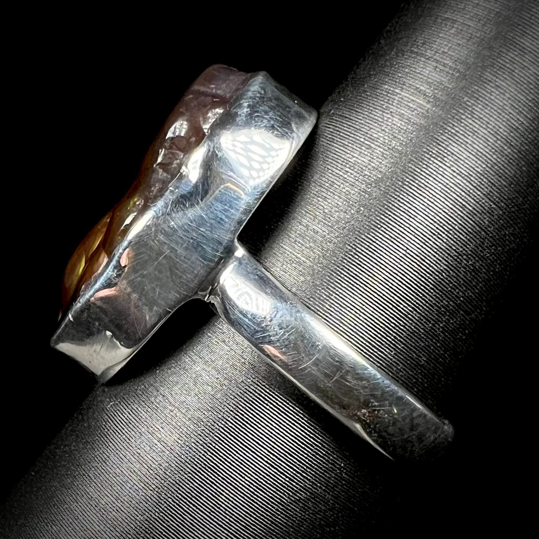 Side view of a sterling silver ring set with a Mexican fire agate stone.
