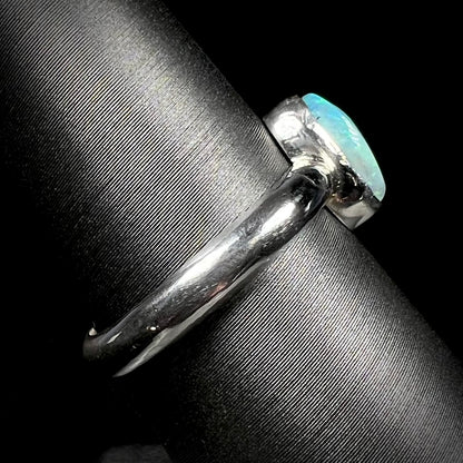 Side close-up view of a handmade sterling silver Australian opal ring on a ring display.  The shank is in focus, and tooling marks can be seen.