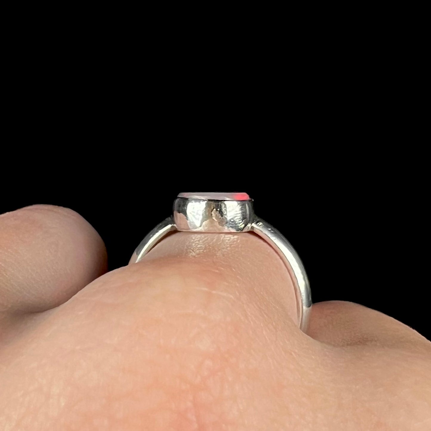 Side profile gallery view of a handmade sterling silver opal ring, worn on a hand.