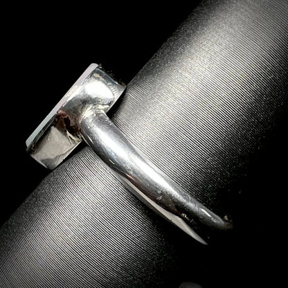 Side shank view of a handmade sterling silver solitaire opal ring on a ring display.  The shank and opal's bezel setting are in view.