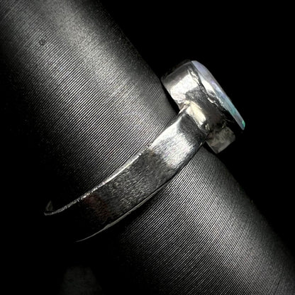 Side view of a unisex opal ring on a ring display.  The handmade sterling silver shank is in focus.