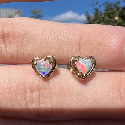 Yellow gold natural opal heart stud earrings.  The earrings have bright red and blue colors.