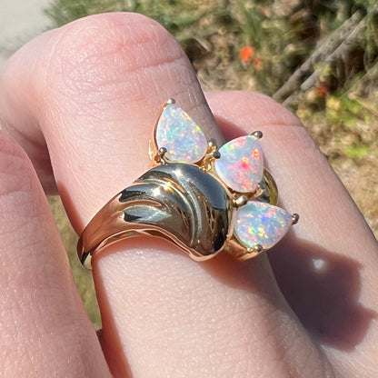 Yellow gold Australian crystal opal ring worn on finger, shown from angle in natural light; a high-polish domed Modernist design detail is in focus.