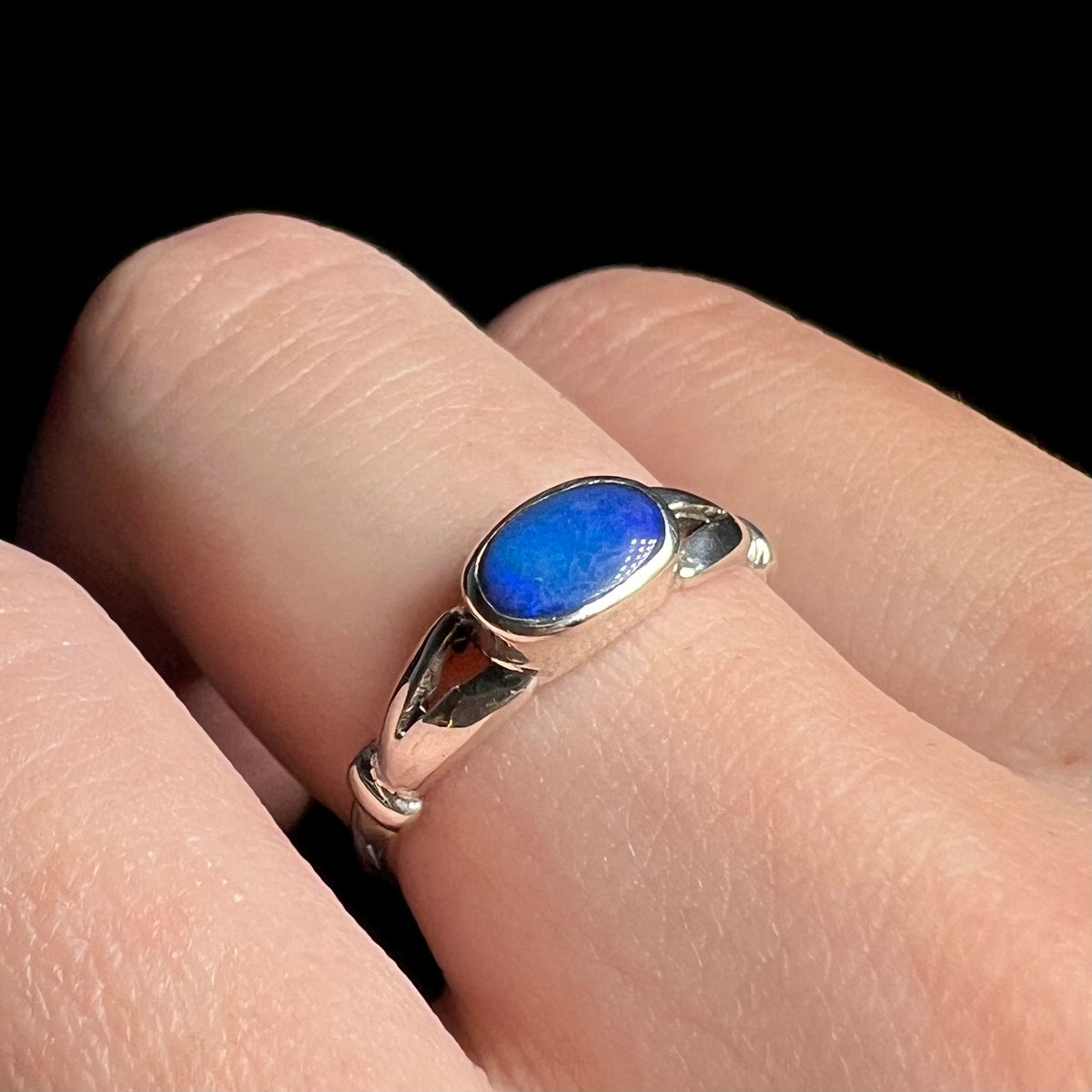 Macro view of horizontally-mounted opal doublet ring in sterling silver, worn on finger