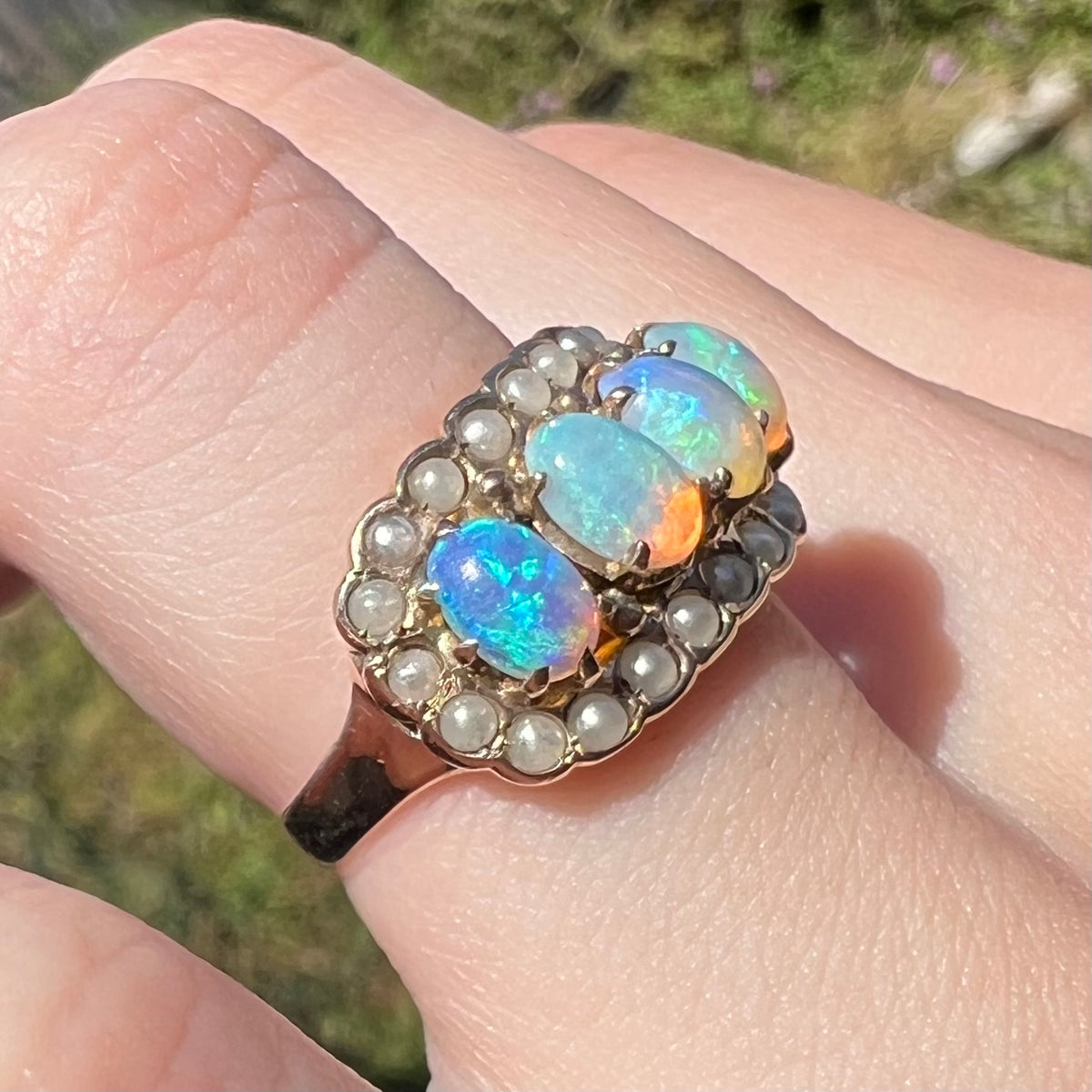 Antique Hungarian crystal opal and seed pearl ring in 9k gold, worn on finger under natural light