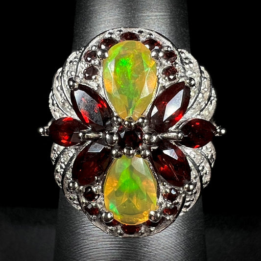 A silver infinity-design ring set with Ethiopian opals, garnets, and diamonds, shown from the front.