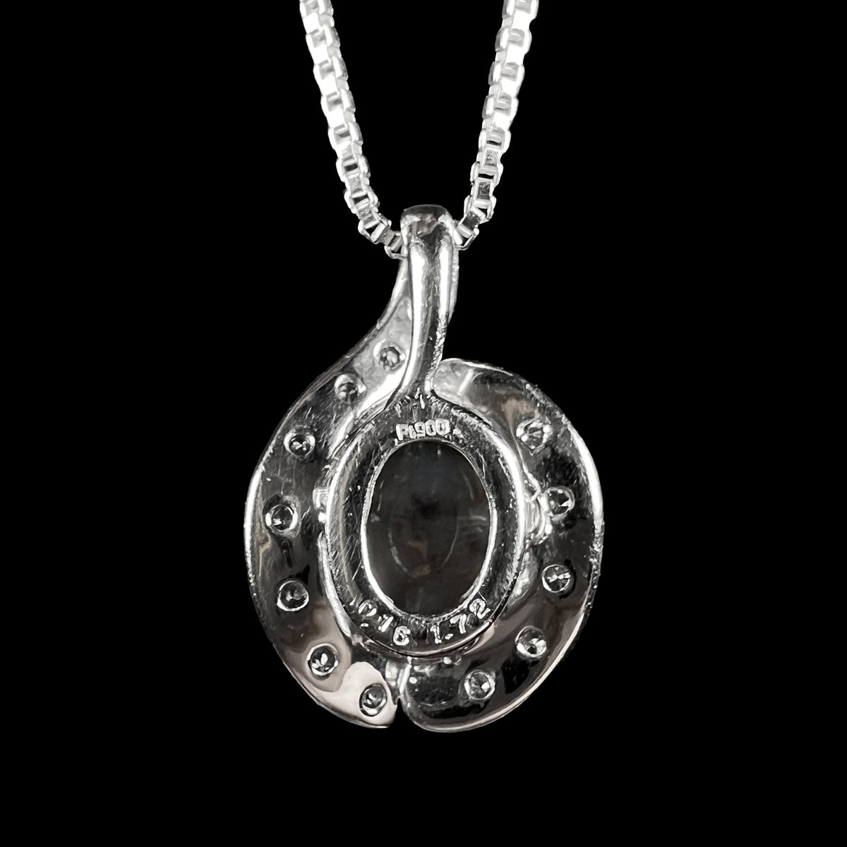 Back side of Japanese platinum pendant showing "Pt900", "0.16", and "1.72" hallmark stamps, as well as the back of the mounted black crystal opal.