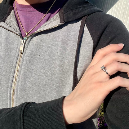 A platinum jelly opal engagement ring in natural sunlight, resting on a model's hand.