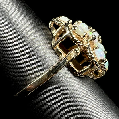 Side view of of a J.M. Fox-made vintage opal cluster ring on a ring display, focused on the ring's yellow gold shank.
