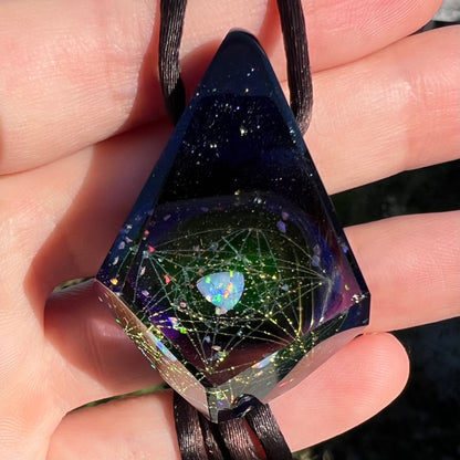 Close-up of an opal in faceted glass pendant, cut by Josh Arleth, shown held by a hand in the sunlight.