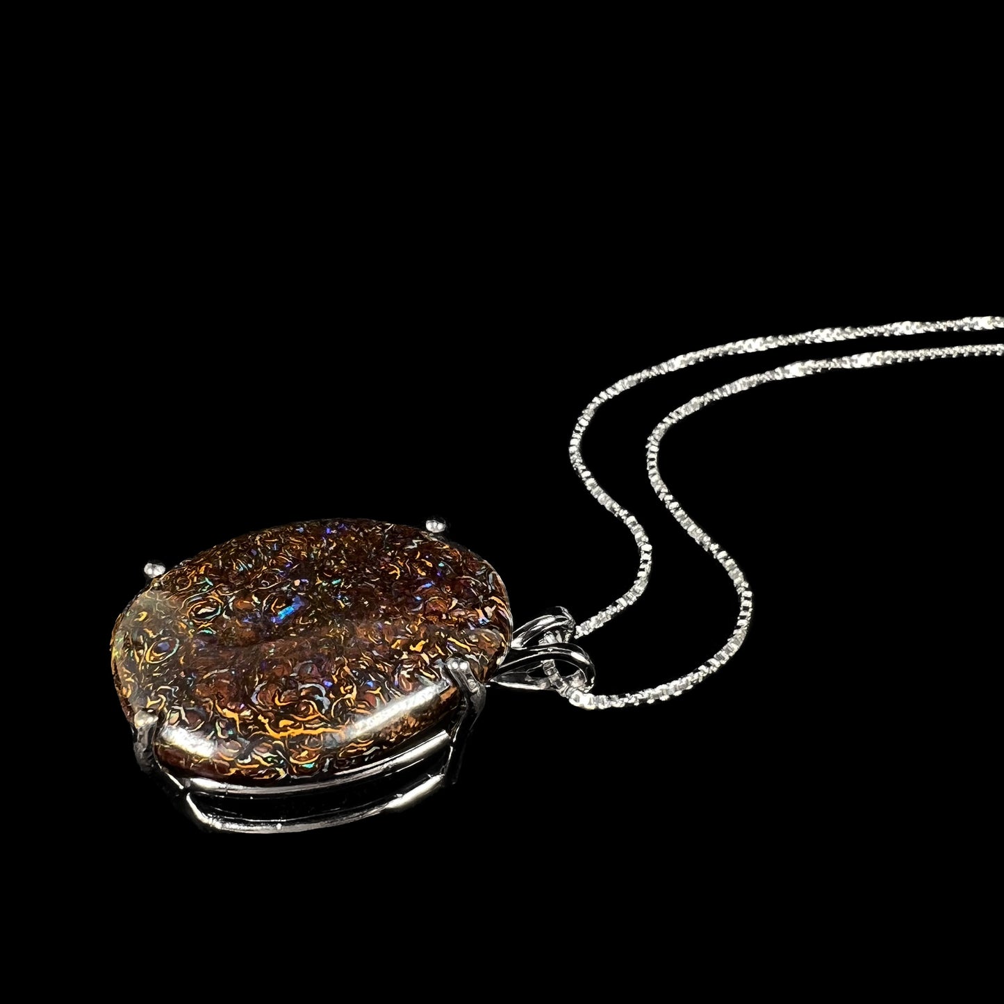 A stylistic angled shot of a Koroit boulder opal necklace, highlighting its organic ironstone patterns and blue pinfire colors.