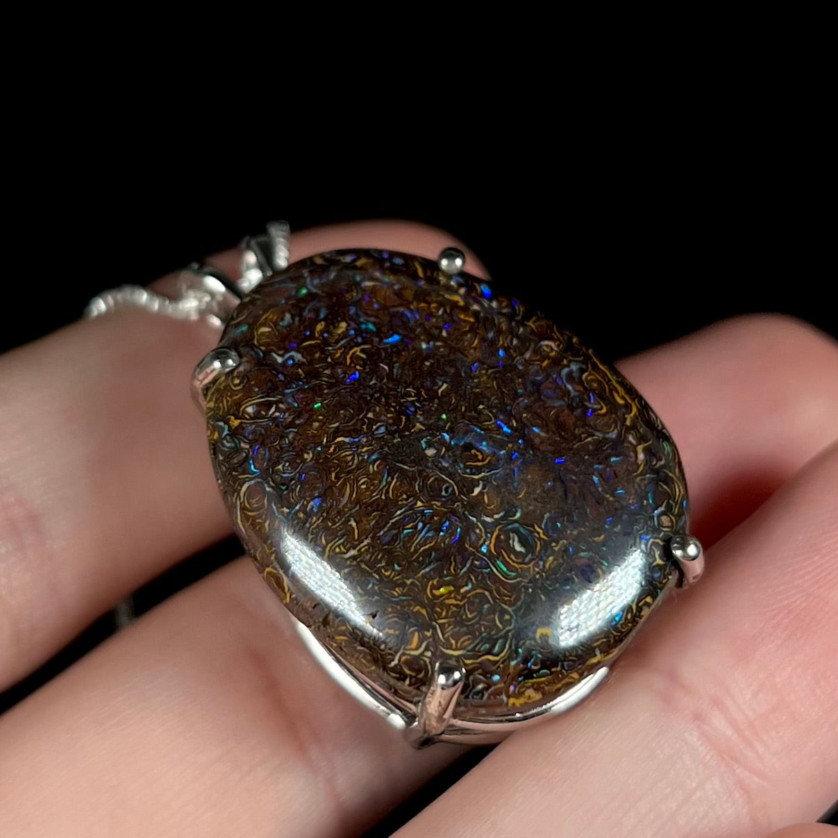 A detailed macro shot of the opposite side of a Koroit boulder opal necklace, showing the natural stone's unique ironstone patterns and blue flashes.