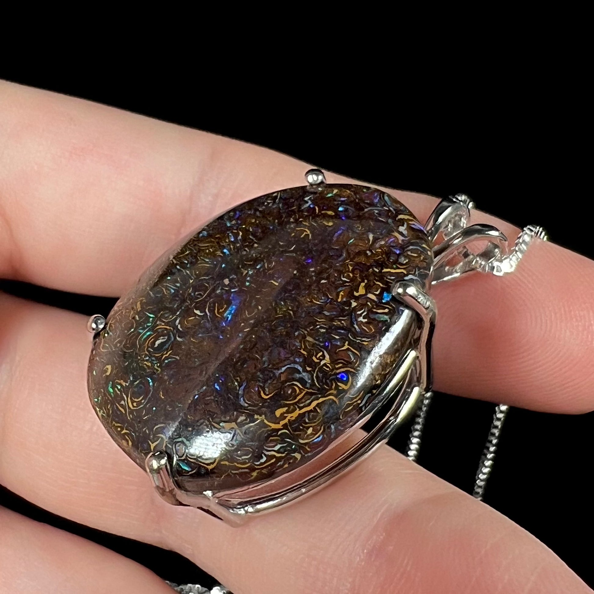 A close-up angled macro view of a Koroit boulder opal necklace, revealing the depth of its ironstone matrix and subtle blue fire.