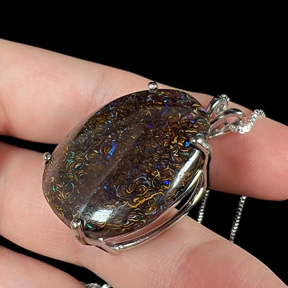 A close-up angled macro view of a Koroit boulder opal necklace, revealing the depth of its ironstone matrix and subtle blue fire.