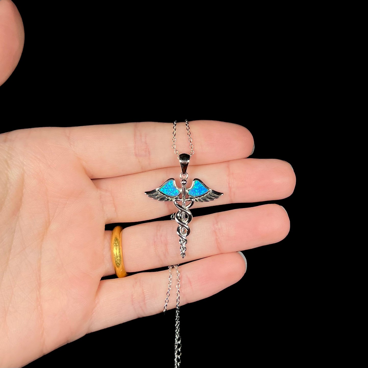 A silver plated medical caduceus pendant with blue lab-created opal inlay.