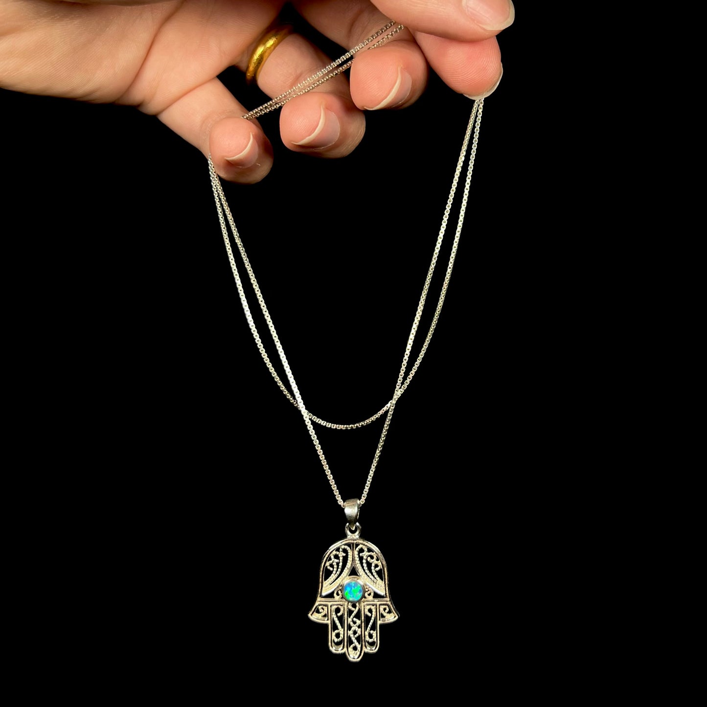 A sterling silver and filigree-accented hamsa hand necklace set with a round lab-created opal.