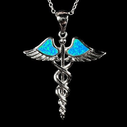 A silver plated medical caduceus pendant with blue lab-created opal inlay.
