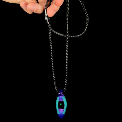 A lab opal boro glass necklace by artist, Within A Sphere, dangled from its black cord by a hand.